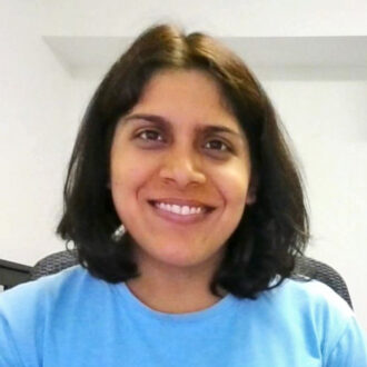 Portrait of a person with shoulder-length brown hair wearing a blue top, smiling.